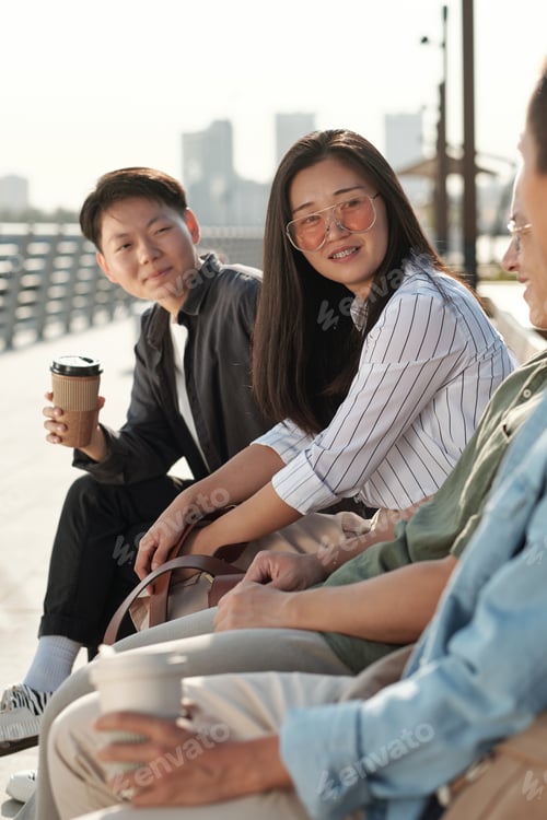 Preview: Contemporary business people sitting on bench during discussion