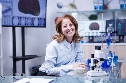 Preview: Smiling senior doctor woman working with microscope at laborator