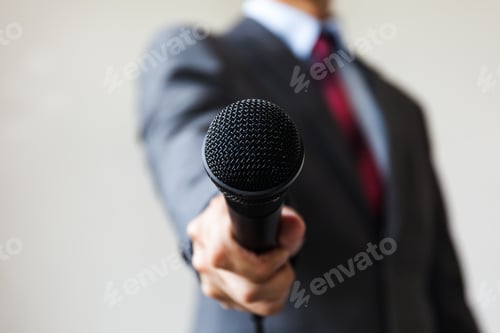Preview: Man in business suit holding a microphone