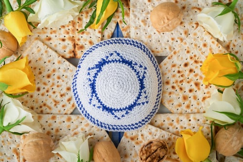 Preview: Passover celebration concept. Blue Star of David made from matzah, white and yellow roses, kippah an