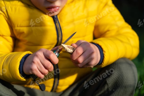 Preview: Boy sharpening a stick to make an arrow with a utility knife