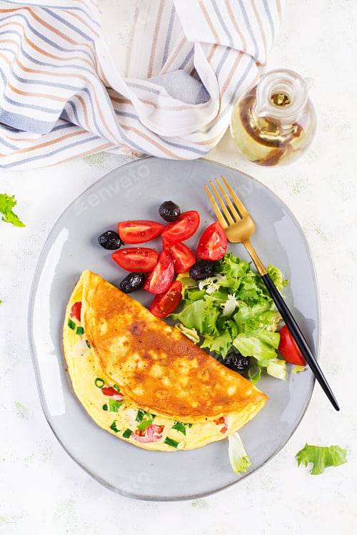 Preview: Omelette with cheese, tomatoes and green onions on light table.
