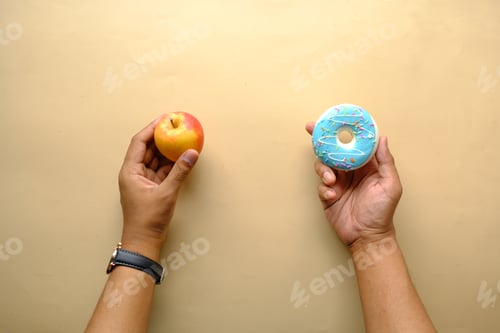 Vorschau: Hand haltend Donuts und Apfel in der Hand auf blauem Hintergrund