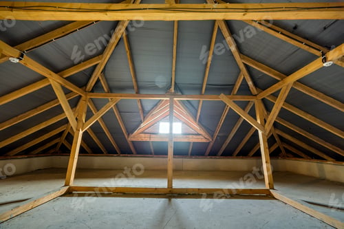 Preview: Attic of a building with wooden beams of a roof structure and a small window.
