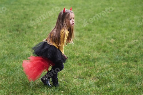 Preview: Portrait of girl in a Halloween devil costume with horns. Happy childhood. All Saints Day.