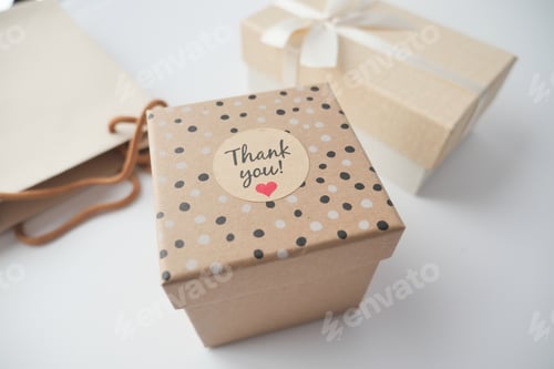 Preview: hand putting a thank you sticker on a gift box