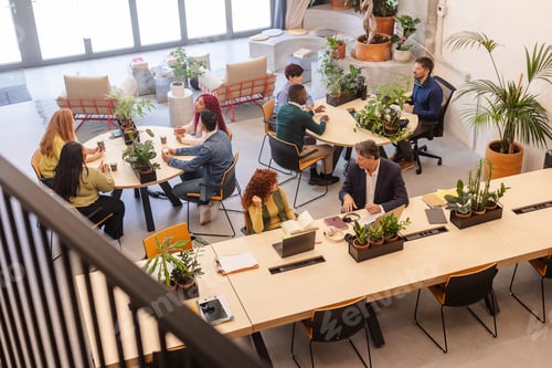 Preview: Coworkers collaborating in modern green office space
