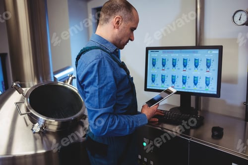 Preview: Manufacturer holding digital tablet while working on computer