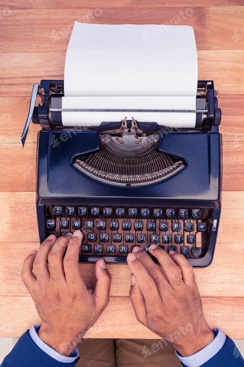 Preview: Businessman typing on typewriter at wooden desk in office