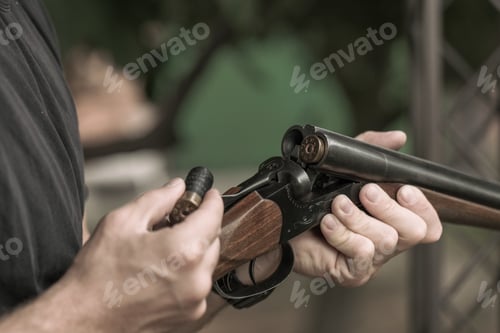 Preview: Man charging double-barreled hunting rifle closeup