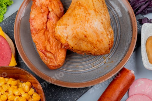 Preview: top view of parts of chicken on a bowl on a marble kitchen board with sweet corns on a wooden bowl