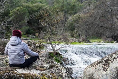 Preview: Closeup shot of a female relaxing in nature next to a waterfall in the river