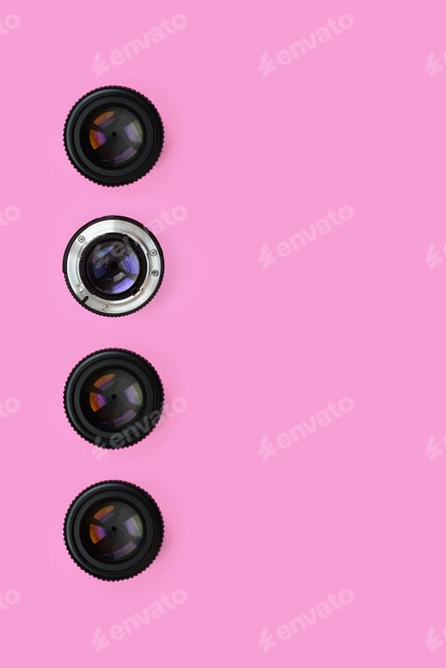 Preview: A few camera lenses with a closed aperture lie on texture background of fashion pastel pink