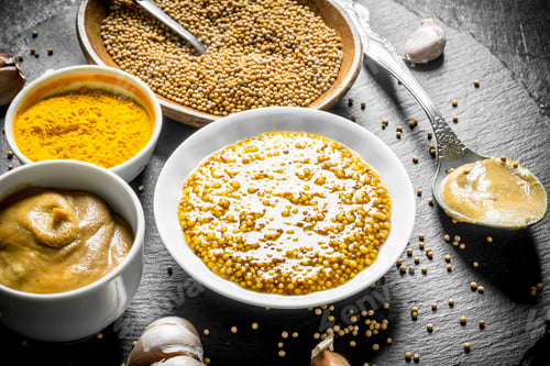 Preview: Assortment of different types of mustard on a stone Board.