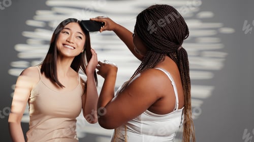 Preview: Beautiful woman brushing hair of her friend on camera