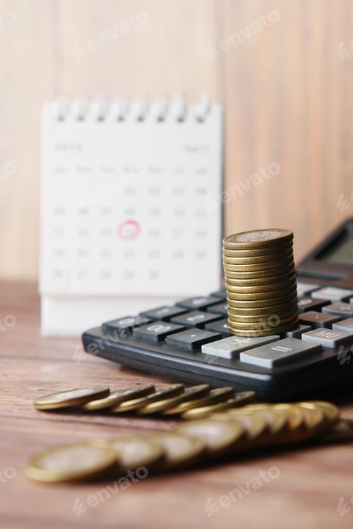 Preview: stack of coins , calculator and calendar on table