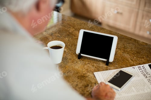 Preview: Senior man looking at digital tablet in the kitchen