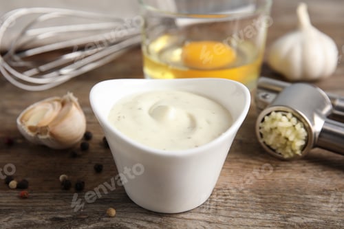 Preview: Composition with bowl of garlic sauce on wooden table