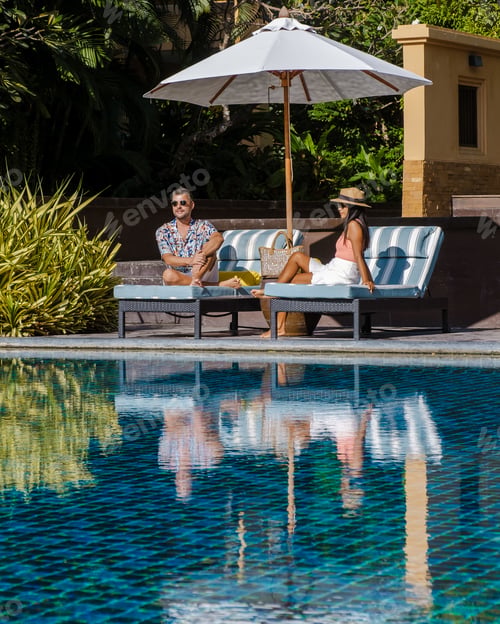 Preview: a young couple of men and women at a swimming pool during a vacation on a tropical island