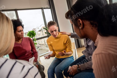 Preview: Diverse group of people sitting in circle in group therapy session.