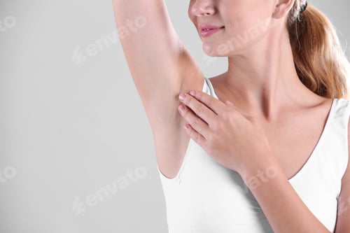 Preview: Young woman showing armpit on grey background, space for text. Using deodorant