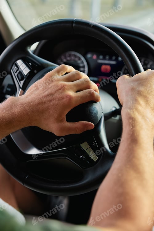 Preview: Close up of a person s hands gripping a steering wheel while driving in a car The dashboard is
