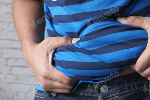 Preview: man's hand holding excessive belly fat, overweight concept