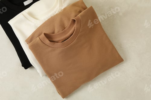 Preview: Stylish folded sweatshirts on white background, top view