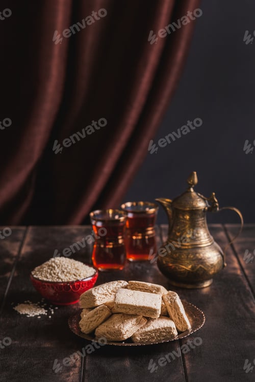 Preview: Pieces of tahini halva, sesame seeds in a bowl, tea in Turkish armudas, an vintage jug.