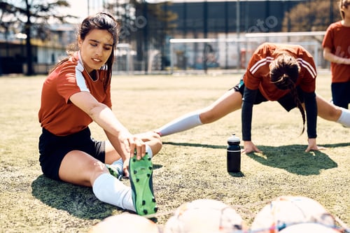 Preview: Female soccer player and her teammates warming up on playing field before the match.
