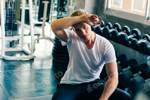Preview: Young man wiping sweat off forehead in gym