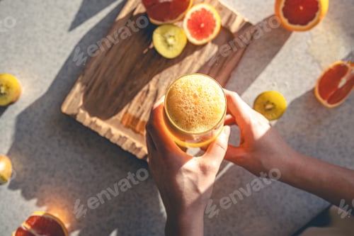 Preview: Woman hand with juice glass and oranges on kitchen table background., top view.