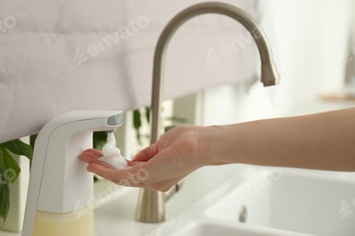 Preview: Woman using automatic soap dispenser in kitchen, closeup