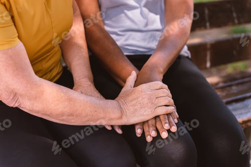 Preview: Diverse women holding hands on bench, showing support, care and friendship