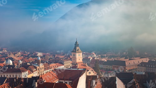 Preview: View of Brasov, Romania, mountains and fog, beautiful historical center with orange houses.