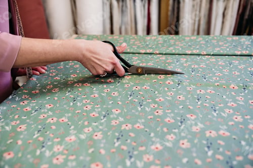 Preview: senior woman working in atelier shop with rolls of fabrics. Cutting fabrics. Small business