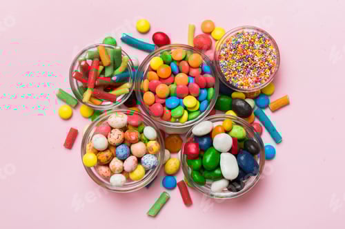 Preview: different colored round candy in bowl and jars. Top view of large variety sweets and candies