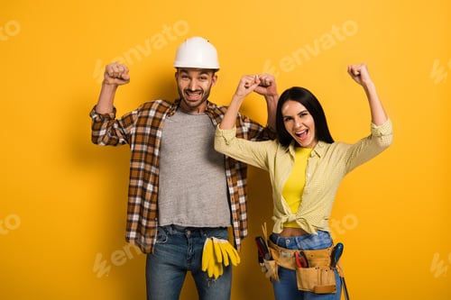 Preview: successful manual workers with hands up on yellow