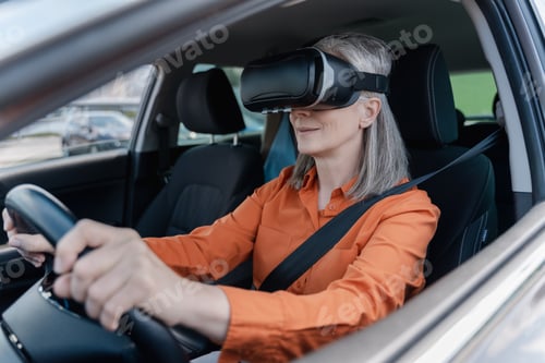 Preview: Mature gray haired woman driver with fastened seat belt, wearing VR glasses, driving a car