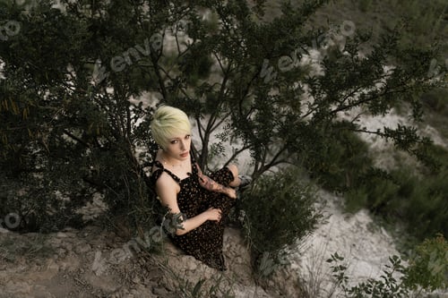 Preview: a woman of non-standard appearance sits on a ledge of a mountain