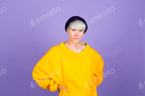 Preview: Stylish european woman on purple background posing wearing yellow large jacket and hat