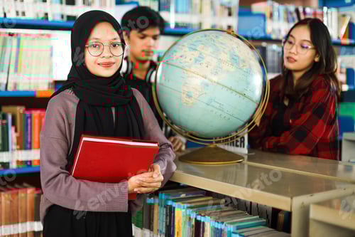 Preview: Smart female Asian girl looking at camera smiling while her classmates looking to world globe