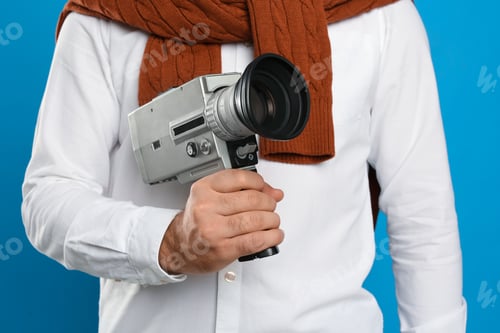 Preview: Man with vintage video camera on light blue background, closeup