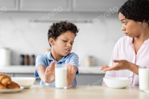 Preview: Boy rejecting glass of milk in kitchen scene
