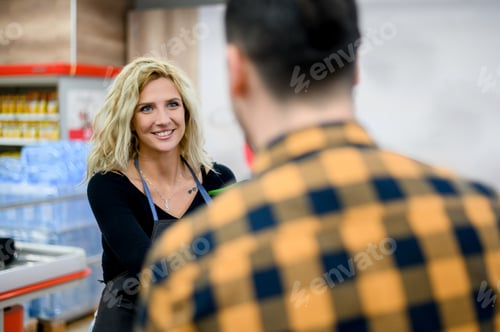 Preview: Beautiful young cashier is smiling while working at the supermarket