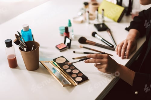 Close up make up artist sitting at the desk withbvariety of cosm