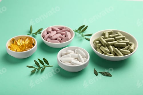 Preview: Different vitamin capsules in bowls and leaves on turquoise background