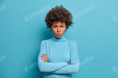 Vista previa: Horizontal shot of dark skinned woman keeps arms folded and looks with offended expression at camera