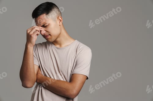 Preview: Displeased handsome guy with headache holding on to his nose