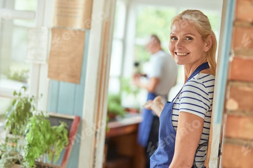 Preview: Middle aged caucasian woman welcoming into garden house